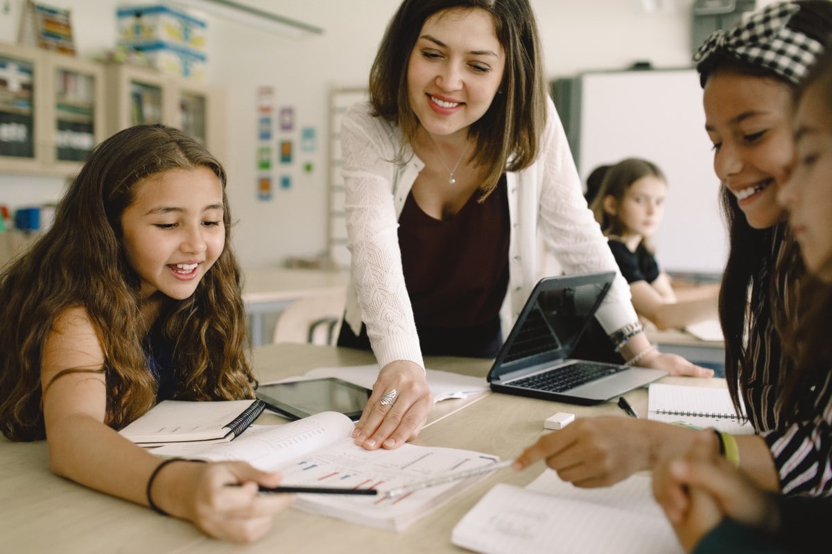 Students learning with a teacher at a desk